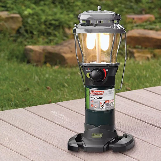 Coleman propane lantern glowing on an outdoor patio table